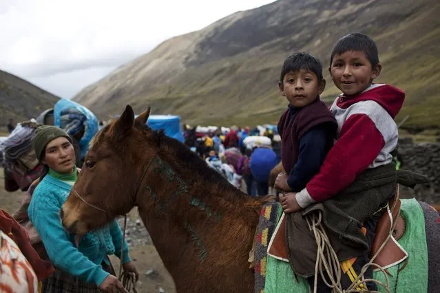 In this May 24, 2016 photo, children mount a horse after breaking camp at the base of the Qullqip'unqu mountain, in the Sinakara Valley, in Peru's Cusco region, where they spent the last 3 days at the Sanctuary of the Lord of the Qoyllur Rit’i, taking part in the festival of the same name, translated from the Quechua language as Snow Star. The gathering is held every year shortly before the Christian feast of Corpus Christi and draws as many as 100,000 people to the Quispicanchis province. It also coincides with the reappearance of the star cluster Pleiades in the Southern Hemisphere, signaling the harvest season. (Photo by Rodrigo Abd/AP Photo)