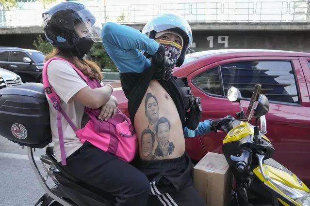 A man displays his tattoos from top; Ferdinand Marcos, Ferdinand “Bongbong” Marcos Jr., and Philippine President Rodrigo Duterte as he passes by BBM headquarters in Mandaluyong, Philippines on Tuesday May 10, 2022. (Photo by Aaron Favila/AP Photo)