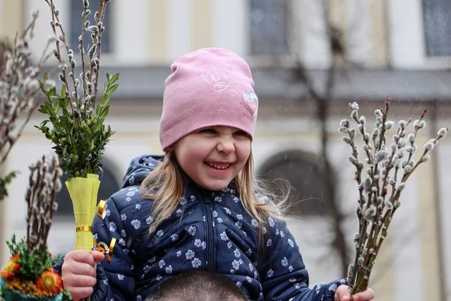 A girl reacts as she holds willow branches during the Palm Sunday celebration, amid Russia's invasion, in Ivano-Frankivsk, Ukraine on April 17, 2022. (Photo by Yuriy Rylchuk/Reuters)