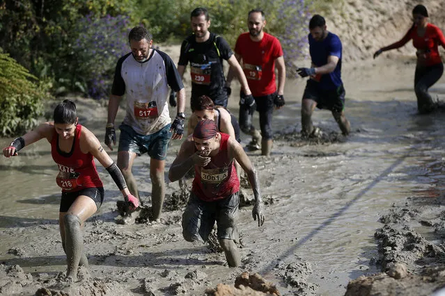 Participants run in the mud during the Mud Day athletic event at El Goloso Military base on the outskirts of Madrid, Spain, Saturday, June 11, 2016. (Photo by Paul White/AP Photo)