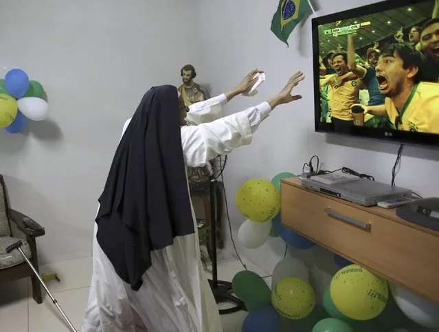 A nun from the enclosed monastery of Imaculada Conceicao celebrates a goal by Brazil during the 2014 World Cup quarter-final soccer match between Brazil and Colombia in Piratininga, in the state of Sao Paulo July 4, 2014. (Photo by Nacho Doce/Reuters)