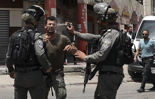 An Israeli border guard sprays pepper gas in the face of a Palestinian protester, during scuffles in the West Bank town of Hauwara, on May 27, 2022. (Photo by Jaafar Ashtiyeh/AFP Photo)