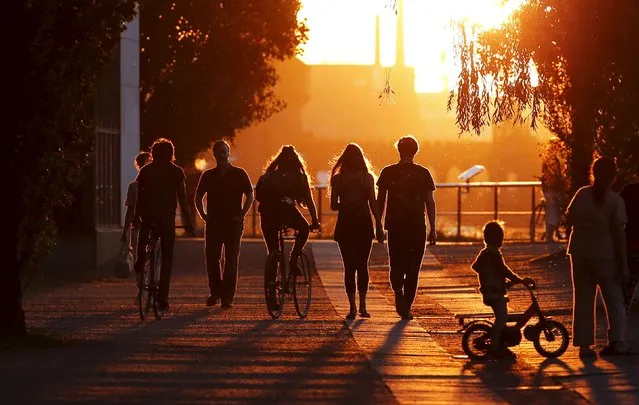 People walk on the embankment at the river Spree during sunset in Berlin, Germany, July 21, 2015. (Photo by Fabrizio Bensch/Reuters)