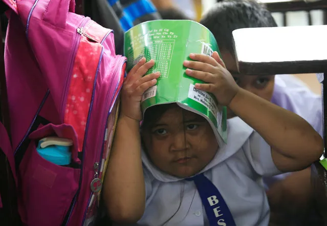 A student uses a book to cover her head during an earthquake drill at the Baclaran Elementary School Unit-1 in Paranaque city, metro Manila, Philippines June 21, 2016. (Photo by Romeo Ranoco/Reuters)