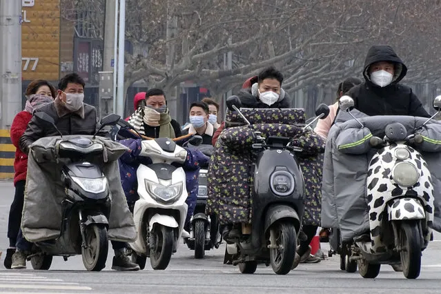 Scooter drivers wear face masks as they wait to cross an intersection in Fuyang in central China's Anhui province, Saturday, January 25, 2020. China's most festive holiday began in the shadow of a worrying new virus Saturday as the death toll surpassed 40, an unprecedented lockdown kept 36 million people from traveling and authorities canceled a host of Lunar New Year events. (Photo by Chinatopix via AP Photo)