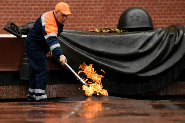 A municipal worker checks the eternal flame in Moscow's Alexander Garden following a storm on May 29, 2017. (Photo by Kirill Kudryavtsev/AFP Photo)