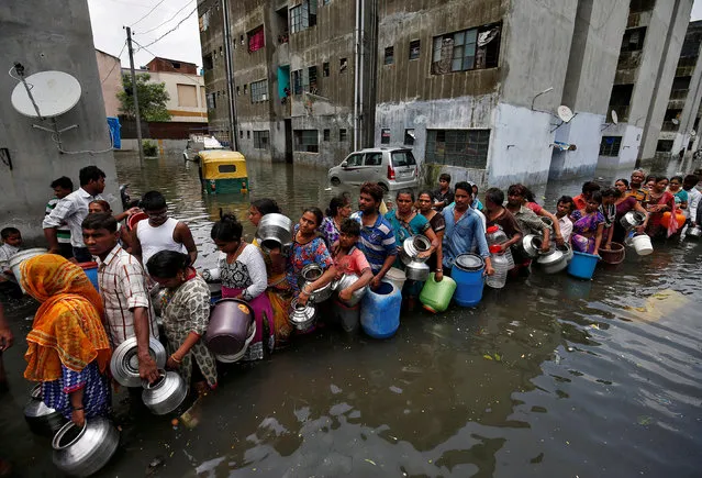 People queue to collect drinking water from a municipal tanker at a flooded residential colony in Ahmedabad, India, July 29, 2017. (Photo by Amit Dave/Reuters)