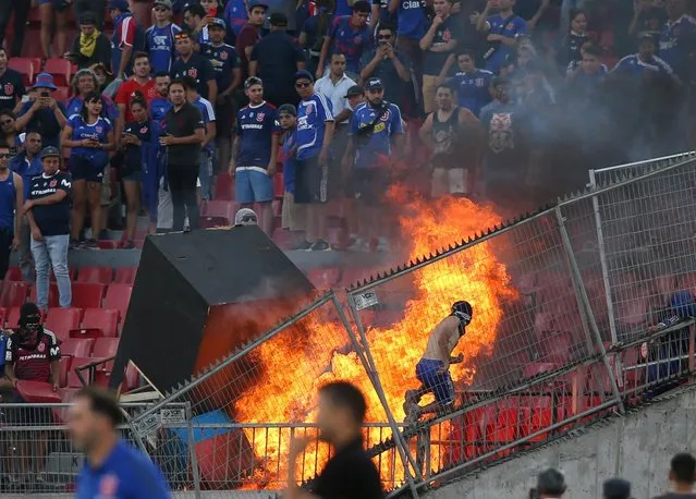 Rioting Universidad de Chile soccer fans light a fire during a series of incidents between the supporters of the University of Chile and the Brazil's International as they play their Copa Libertadores scond round first leg match at the Nacional Stadium in Santiago, Chile, 04 February 2020. (Photo by Edgard Garrido/Reuters)
