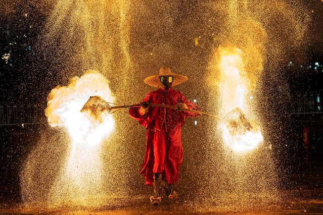 A folk artist performs a stunning fire-pot performance on October 18, 2024 in Guangzhou,Guangdong Province of China.Huohu (fire pot) is a traditional folk performance art.Performers put well-burned charcoal into iron meshes on both sides and shake the meshes up and down so that the charcoal will flare up and blazing sparks will burst out of the meshes and light up the sky just like fireworks. (Photo by John Ricky/Anadolu via Getty Images)