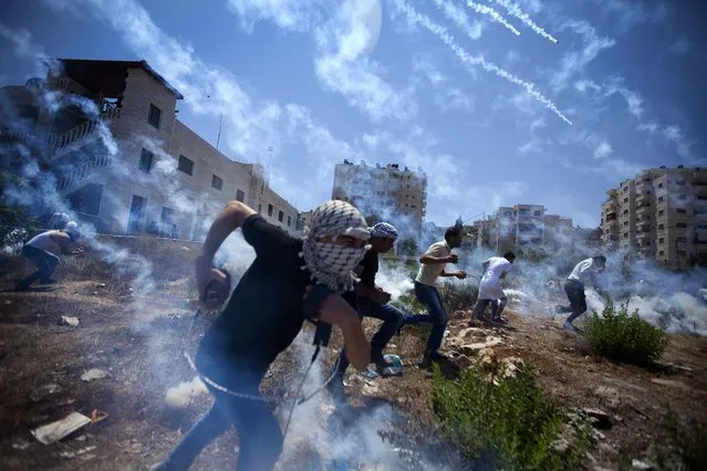 Palestinians run for cover during clashes with Israeli soldiers following a protest against the war in the Gaza Strip, outside Ofer, an Israeli military prison near the West Bank city of Ramallah, on August 1, 2014. (Photo by Majdi Mohammed/Associated Press)