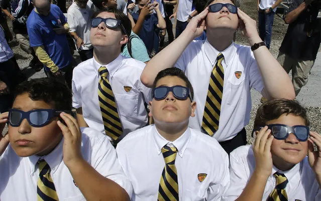 Belen Jesuit Preparatory School students look through solar glasses as they watch the eclipse, Monday, August 21, 2017, in Miami. (Photo by Alan Diaz/AP Photo)