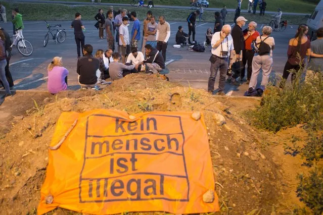 Asylum seekers play cards with immigrant supporters outside the home of asylum seekers located in a shelter in Heidenau, Germany August 23, 2015. Germany's interior minister led calls on Sunday for a crackdown on right-wing militants and racists after a second night of scuffles between protesters and police outside a refugee shelter in an eastern German town near Dresden. (Photo by Axel Schmidt/Reuters)