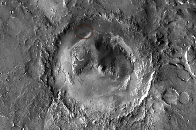 NASA has selected Gale crater as the landing site for the Mars Science Laboratory mission. The mission's rover will be placed on the ground in a northern portion of the crater in August 2012. This view of Gale is a mosaic of observations made in the visible-light portion of the spectrum by the Thermal Emission Imaging System camera on NASA's Mars Odyssey orbiter. Gale crater is 96 miles (154 kilometers) in diameter and holds a layered mountain rising about 3 miles (5 kilometers) above the crater floor. The ellipse superimposed on this image indicates the intended landing area, 12.4 miles (20 kilometers) by 15.5 miles (25 kilometers). The portion of the crater within the landing area has an alluvial fan likely formed by water-carried sediments. The lower layers of the nearby mountain – within driving distance for Curiosity – contain minerals indicating a wet history. (Photo by NASA/JPL-Caltech/ASU)