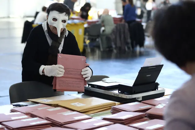 A woman wears a mask and gloves as she prepares postal votes in Munich, Germany, Sunday, March 15, 2020. Germany has been slower than some of its neighbours to ban large gatherings, initially leaving the decision to local authorities as required by country's federal structure. For some, especially older adults and people with existing health problems, it can cause more severe illness, including pneumonia. (Photo by Matthias Schrader/AP Photo)