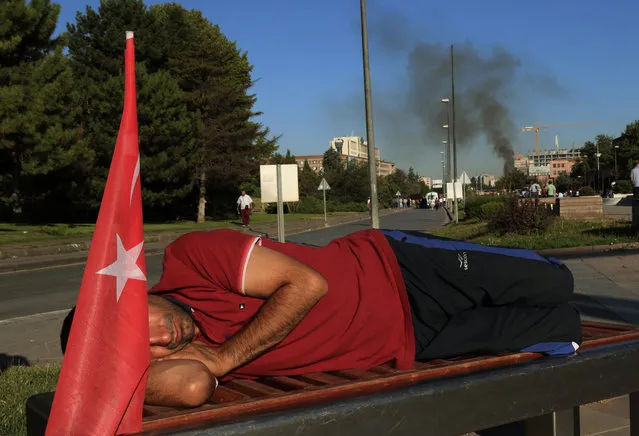 A protester rests on a bench as smoke billows from the Turkish military headquarters, in Ankara, Turkey, Saturday, July 16, 2016. (Photo by Ali Unal/AP Photo)