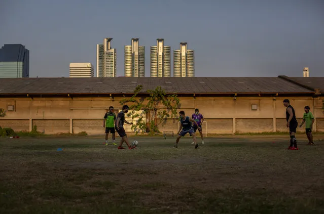 Thai man, some with face masks play a game of soccer in an open lot in Bangkok, Thailand, Wednesday, April 8, 2020. Playgrounds and public parks remained closed as a month-long state of emergency has been enforced in Thailand to allow its government to impose stricter measures to control the coronavirus that has infected hundreds of people in the Southeast Asian country. (Photo by Gemunu Amarasinghe/AP Photo)