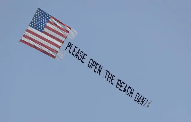 A banner plane flies a sign urging Miami Beach, Fla., Mayor Dan Gelber to open the beaches, which have been closed due to the coronavirus outbreak, Sunday, April 19, 2020, in Miami Beach, Fla. (Photo by Wilfredo Lee/AP Photo)
