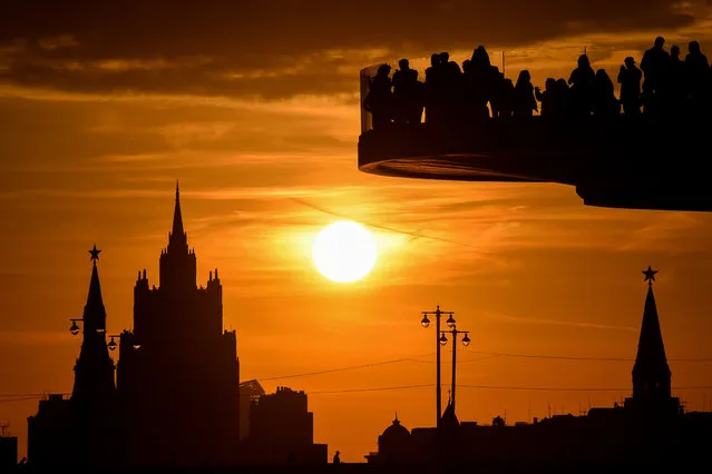People enjoy the view from a pedestrian bridge in the newly-opened Zaryadye Park, with the Kremlin's towers and the main building of the Russian Foreign Ministry seen in the background, as the sun sets in downtown Moscow on September 25, 2017. (Photo by Vasily Maximov/AFP Photo)