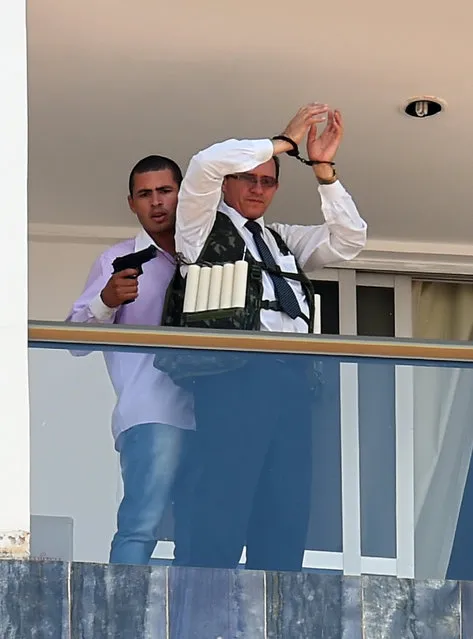 An unidentified man keeps a hotel employee with an explosive-laden vest at a balcony of the hotel in Brasilia on September 29, 2014. (Photo by Evaristo Sa/AFP Photo)