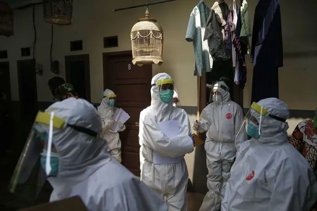 Healthcare workers in hazmat suits stand on a small alley during a door to door covid-19 swap test at a residential area in Jakarta, Indonesia, 12 June 2020. The Indonesian government has imposed a new set of regulations known as “new normal”, which will be implemented in stages, starting in early June for some provinces. Provinces that have either reported no new COVID-19 infections or are reporting a significant drop in infection numbers can reopen businesses while adhering to health code protocols. (Photo by Mast Irham/EPA/EFE/Rex Features/Shutterstock)