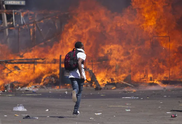 Zimbabwe's opposition supporters set up a burning barricade as they clash with police during a protest for electoral reforms on August 26, 2016 in Harare, Zimbabwe. Riot police in Zimbabwe fired tear gas, beat up protesters and blocked off the site of an opposition rally in Harare on August 26, 2016, the latest in a string of demonstrations to hit the country. The rally – which was authorised by a court – was to demand electoral reforms before 2018 when 92-year-old President Robert Mugabe, who has ruled the southern African country for decades, will seek re-election. (Photo by Zinyange Auntony/AFP Photo)