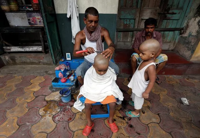 A roadside barber shaves the head of a young boy on a pavement in Kolkata, India, August 29, 2016. (Photo by Rupak De Chowdhuri/Reuters)