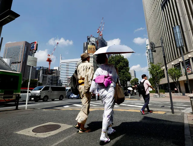A couple wearing Yukata, Japanese summer kimono, walks along a shopping district in Tokyo, August 26, 2016. (Photo by Kim Kyung-Hoon/Reuters)