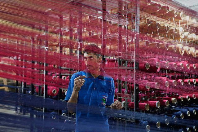 An Indian worker checks thread reels on a carpet weaving machine at a factory on the outskirts of Jammu, India, Tuesday, April 8, 2025. (Photo by Channi Anand/AP Photo)