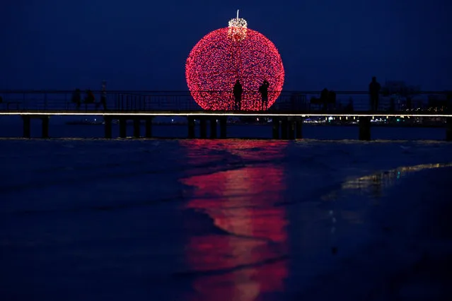 People are seen on a pier in front of a giant illuminated Christmas ball in Larnaca, Cyprus December 19, 2017. (Photo by Yiannis Kourtoglou/Reuters)