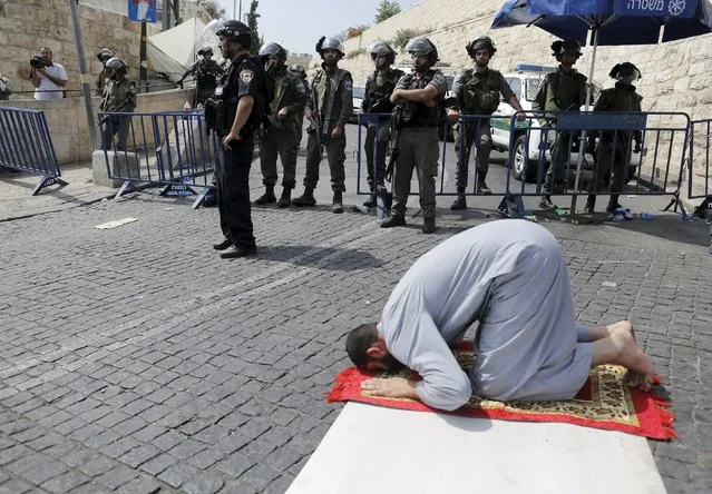 A Palestinian man prays as Israeli policemen guard during Friday prayers outside Jerusalem's Old City near the Arab East Jerusalem neighbourhood of Wadi al-Joz October 2, 2015. (Photo by Ammar Awad/Reuters)