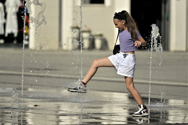 A girl cools off at a fountain in Pristina on July 17, 2023, as Kosovo is hit by a heatwave. (Photo by Armend Nimani/AFP Photo)