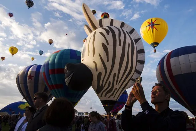A man uses his phone to take pictures as hundreds of hot air balloons lift off on the first day of the 2015 Albuquerque International Balloon Fiesta in Albuquerque, New Mexico, October 3, 2015. (Photo by Lucas Jackson/Reuters)