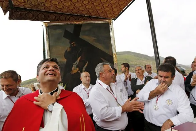 A priest smiles in front of the picture of the Christ of Pano during a pilgrimage in Moclin, southern Spain, October 5, 2015. (Photo by Marcelo del Pozo/Reuters)