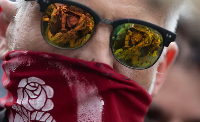 Members of far right militias and white pride organizations are reflected into the glasses of a anti-fascist protester at a rally near Stone Mountain Park in Stone Mountain, Georgia, on August 15, 2020. Militia members, such as III%, were met with anti-racist and anti-fascist protesters organized by F.L.O.W.E.R, a frontline organization based in Atlanta to combat racism. (Photo by Logan Cyrus/AFP Photo)