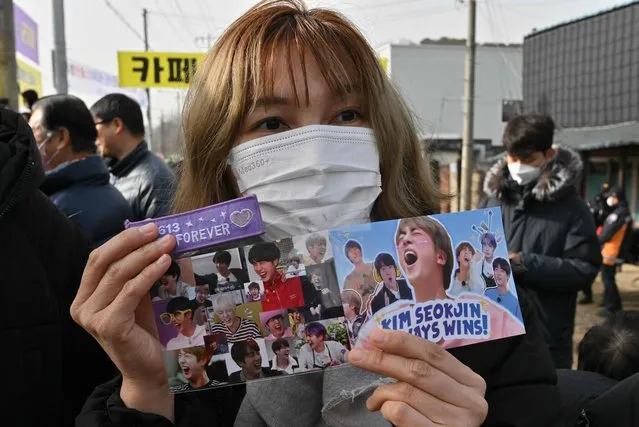 A fan holds pictures of BTS singer Jin in front of a military training unit in Yeoncheon on December 13, 2022, as the place where BTS singer Jin is scheduled to arrive to begin his military service. BTS star Jin starts his mandatory South Korean military duty on December 13, 2022, the first band member to enlist since their hiatus announcement this year left fans heartbroken and wondering if this was the end for the K-pop juggernaut. (Photo by Jung Yeon-je/AFP Photo)