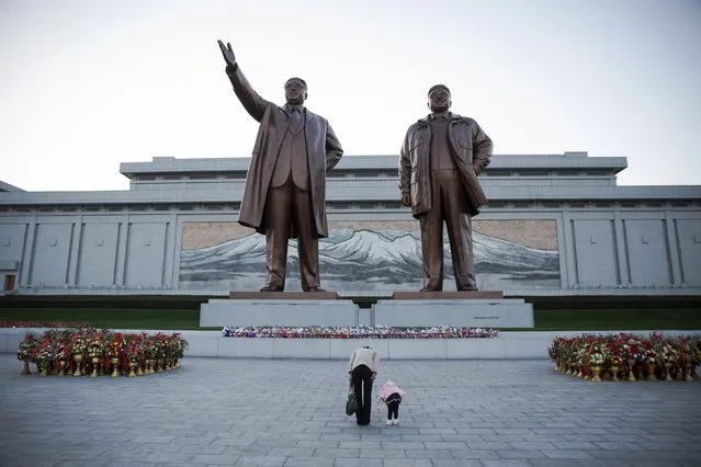 A woman and her daughter their respects at statues of North Korea founder Kim Il Sung (L) and late leader Kim Jong Il in Pyongyang October 11, 2015. (Photo by Damir Sagolj/Reuters)