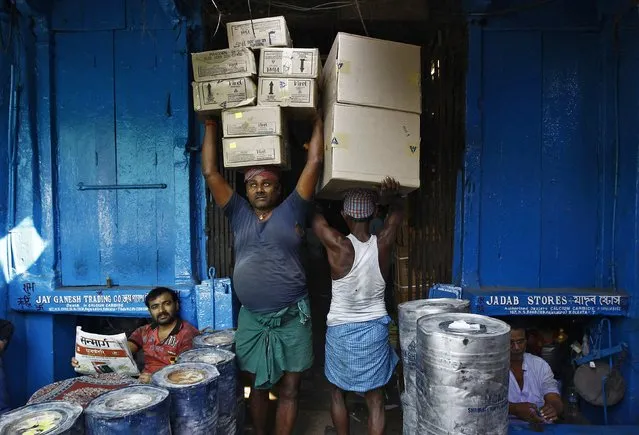 Labourers carry grocery items at a wholesale market in Kolkata November 14, 2014. India's inflation dropped to a new multi-year low in October, helped by slower annual rises in food and fuel prices, intensifying pressure on the central bank to cut interest rates to encourage spending and investment needed to boost growth. (Photo by Rupak De Chowdhuri/Reuters)