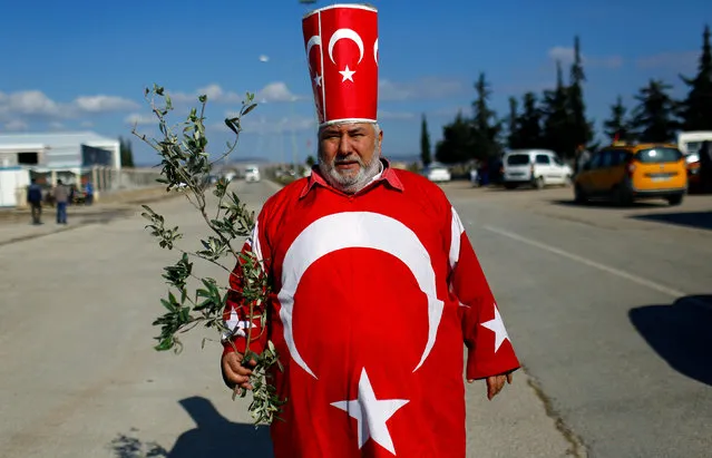 Mehmet Agagurbuz, known as Isikli tosun baba, is pictured dressed in Turkish flags holding an olive branch, as he visits Oncupinar border gate to show his support to the Turkish Armed Forces on the Turkish-Syrian border in Kilis, Turkey, January 28, 2018. (Photo by Murad Sezer/Reuters)
