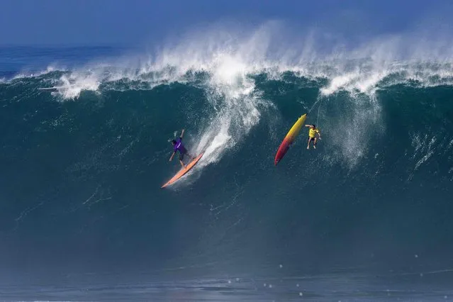 US surfer Eli Olsen rides a wave as Hawaiian surfer Jake Maki gets wiped out during The Eddie Aikau Big Wave Invitational surfing contest on January 22, 2023, at Waimea Bay on the North Shore of Oahu in Hawaii. (Photo by Brian Bielmann/AFP Photo)