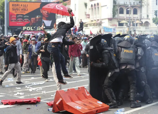 A protester tries to hurl a brick towards police trying block protesters from advancing towards the Presidential Palace during a rally in Jakarta, Indonesia, Thursday, October 8, 2020. (Photo by Achmad Ibrahim/AP Photo)