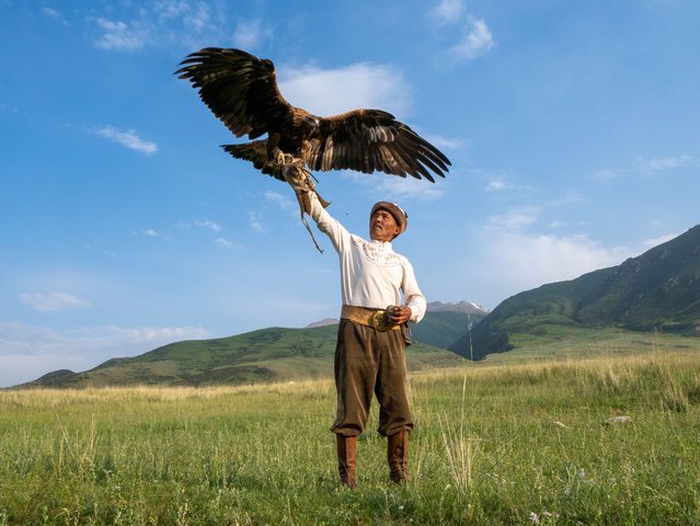 A traditional Kyrgyz man holds an eagle on his hand as the centuries-old tradition of eagle training, known as “Munushkor”, is making a comeback in Issyk-Kul, Kyrgyzstan on July 27, 2025. In this cultural practice, trainers called 'burkutchi' capture young eagles from nature and raise them through a dedicated training process. Once the training is complete, the birds are traditionally released back into the wild. Once on the brink of extinction during the Soviet era, the tradition is now being revived with interest from younger generations. Beyond being a method of hunting, eagle taming is regarded as a symbol of patience, loyalty, and cultural heritage. (Photo by Umut Karahasanoglu/Anadolu via Getty Images)
