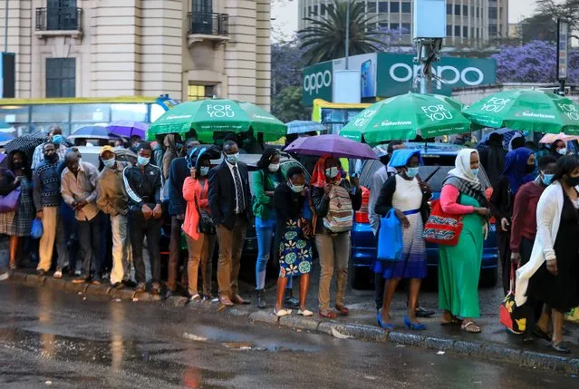 People wearing face masks que at a bus stop without adhering to social distancing as it rains in Nairobi, Kenya, 19 October 2020. In recent days the numbers of COVID-19 coronavirus cases have been on the rise around the country, after the government eased the coronavirus restrictions for economic activities including curfew hours, re-opening of schools and bars which is now feared may trigger a resurgence. (Photo by Daniel Irungu/EPA/EFE)