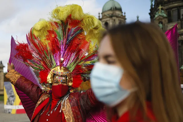 A man in a costume wears a face mask and dances as he attends a protest of people working in the entertainment and entertainment industry against the German government's economic policies to combat the spread of the coronavirus and COVID-19 disease and demand more support for their business, in Berlin, Germany, Wednesday, October 28, 2020. (Photo by Markus Schreiber/AP Photo)