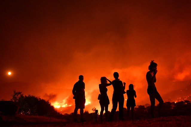 Residents look at flames as a wildfire rages near Palaia Fokaia, some 45 Km south of Athens, on August 8, 2025. (Photo by Aris Messinis/AFP Photo)