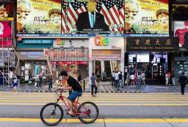 Pedestrians cross the street at a zebra crossing as Republican candidate Donald J. Trump speaks during a live news report about the US presidential election broadcasting on a large screen in Hong Kong on November 4, 2020. (Photo by Miguel Candela/SOPA Images/Rex Features/Shutterstock)