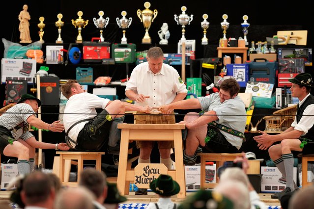 A referee monitors the leather ring held by two competitors with their middle fingers at the German Championships in Fingerhakeln or finger wrestling, in Bernbeuren, Germany, Sunday, May 12, 2024. Competitors battled for the title in this traditional rural sport where the winner has to pull his opponent over a marked line on the table. (Photo by Matthias Schrader/AP Photo)