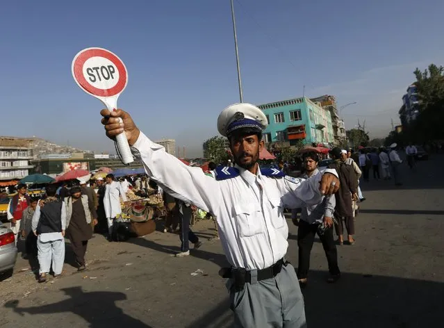 An Afghan traffic policeman directs vehicles on a busy road in Kabul August 31, 2014. (Photo by Mohammad Ismail/Reuters)