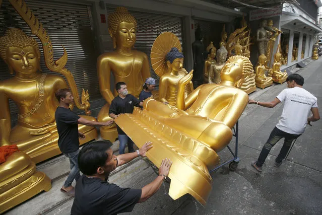 Thai workers remove a Buddha statue at a shop in Bangkok, Thailand, Tuesday, July 4, 2017, in preparation for the upcoming Buddhist Lent. Buddhist monks return to their monasteries to study the teachings of Lord Buddha during the three-month long Buddhist Lent, which starts on July 9, 2017. (Photo by Sakchai Lalit/AP Photo)