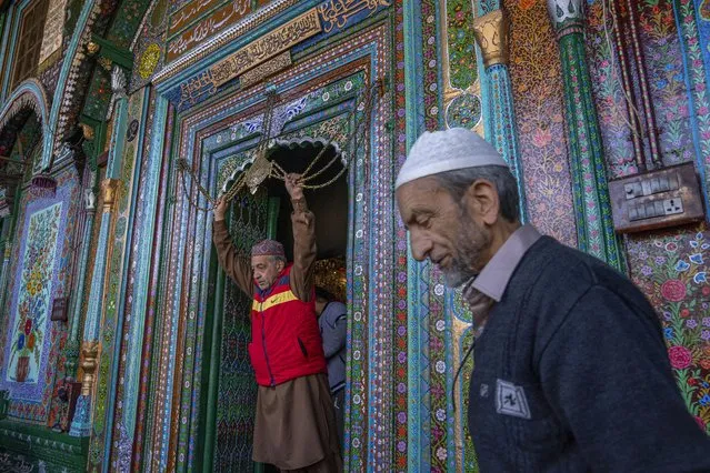 A Kashmiri man, left, touches in reverence a chain at the entrance to the shrine of Shah-e-Hamadan as he leaves after offering prayers on the third Friday of Ramadan in Srinagar, Indian controlled Kashmir, Friday, April 7, 2023. Muslims across the world are marking the holy month of Ramadan, a period of intense prayer, self-discipline, dawn-to-dusk fasting and nightly feasts. (Photo by Dar Yasin/AP Photo)