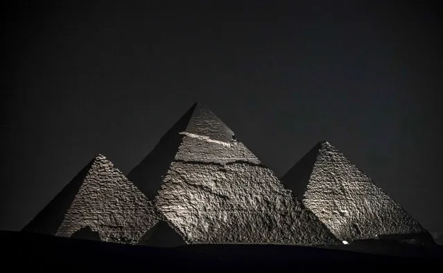 This picture taken on October 20, 2020 shows a general view of (R to L) the Great Pyramid of Khufu (Cheops), the Pyramid of Khafre (Chephren), and the Pyramid of Menkaure (Menkheres) at the Giza Pyramids necropolis on the southwestern outskirts of the Egyptian capital Cairo during an official ceremony launching the trial operations of the site's first environmentally-friendly electric bus and restaurant as part of a wider development plan at the necropolis. (Photo by Khaled Desouki/AFP Photo)